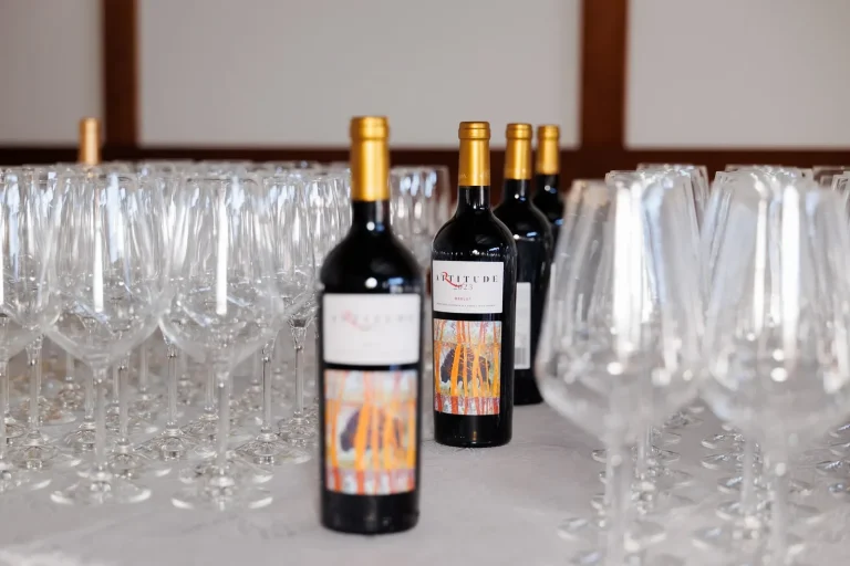 Bottles of Artitude red among rows of empty wine glasses on the tasting table