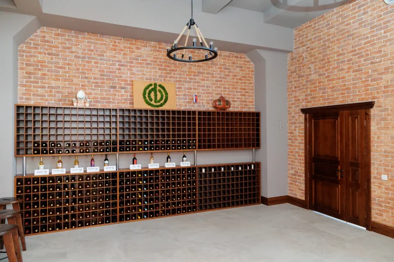 Sala de degustare a cramei, cu rafturi de vin pe un perete de cărămidă și o ușă de lemn